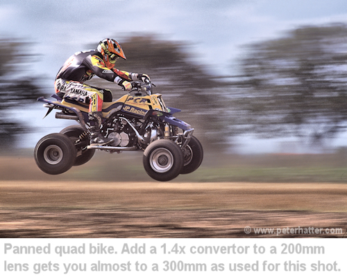 a quad bike panned as it goes over a jump.